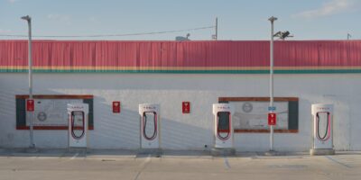 Four Tesla Supercharger stalls against the wall of a roadside burger restaurant in Inyokern, California