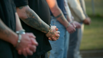 Handcuffed participants standing in line in the Netflix series The New Stanford Prison Experiment