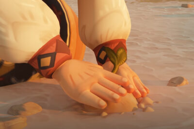 Hands pressing a green sprout into dry sand in The Regreening
