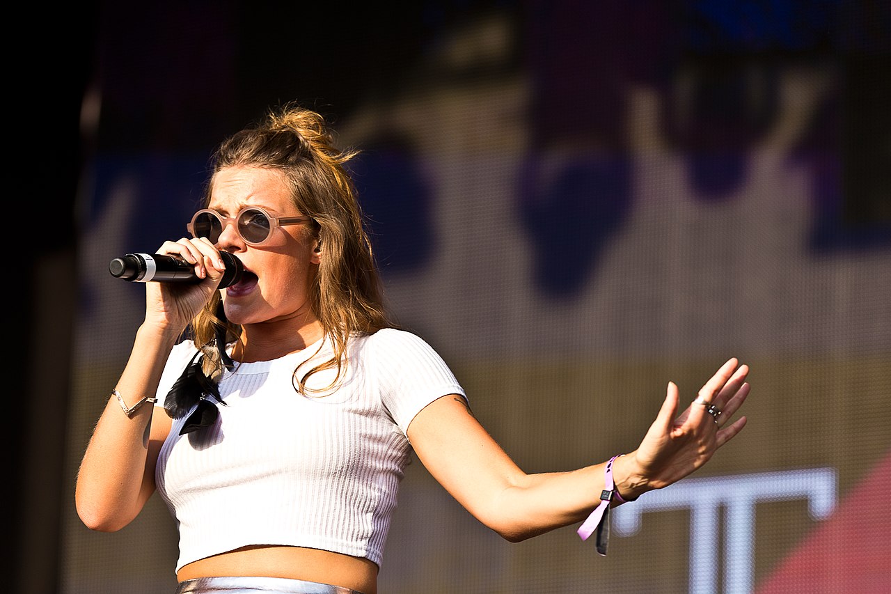 Tove Lo singing into a microphone on stage at Melt! Festival 2015, wearing round sunglasses and a white crop top