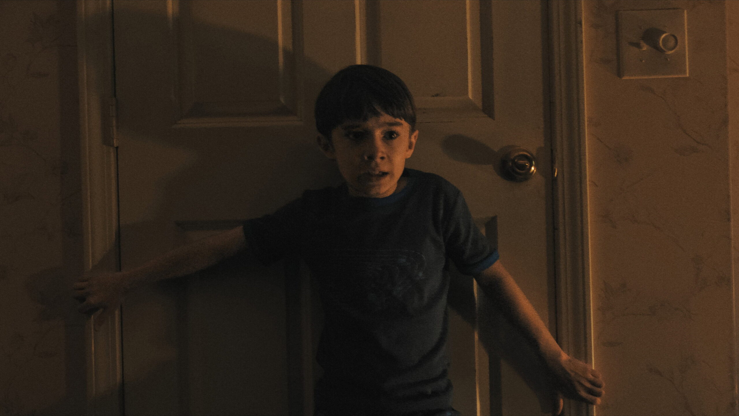Cary Christopher como Alex, el único niño que queda en su clase, pegado a una puerta en Weapons