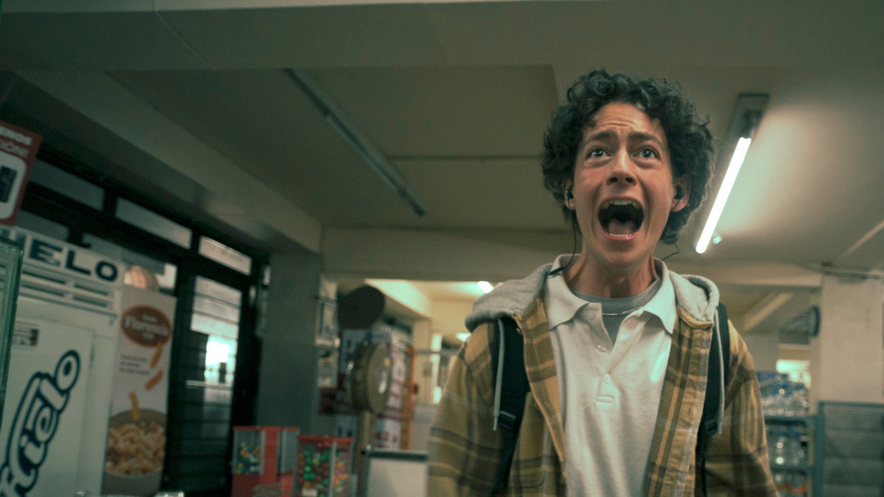 Diego Bernal as Archie screaming inside a fluorescent-lit corner shop in a still from the Prime Video series I Would Rather Die