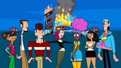 From left to right: Frida Kahlo, Abe Lincoln, JFK, Joan of Arc, Harriet Tubman, Cleopatra, and Confucius stand in front of the Grassy Knoll as it burns